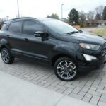 Black compact crossover parked on brick driveway