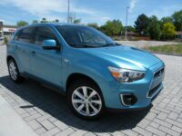 Blue compact SUV parked on brick pavement
