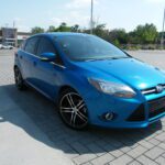 Blue hatchback parked on paved brick driveway