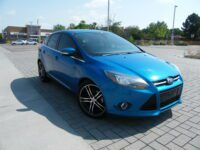 Blue hatchback parked on paved brick driveway